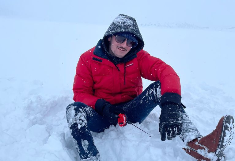 Antoine est assis dans la neige et pêche